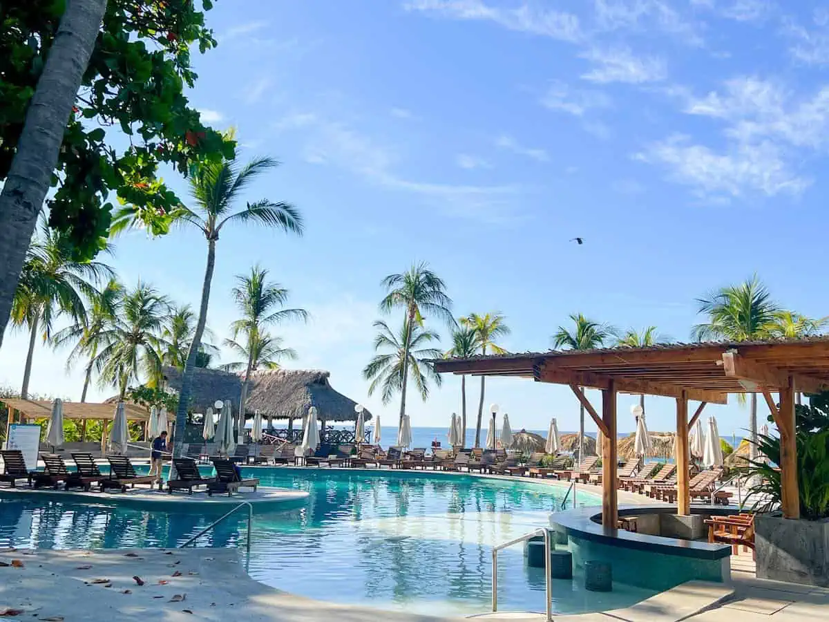 Pool bar at Villasol Beach Club with palm trees and sea view. 