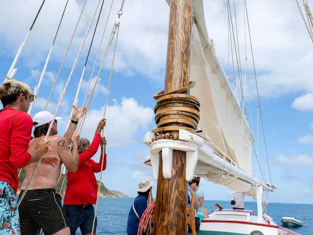 People pulling the sails on a sail boat. 