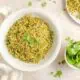 A bowl of arroz verde on the table with cilantro leaves.