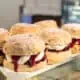 Six scones with clotted cream in a London bakery window.